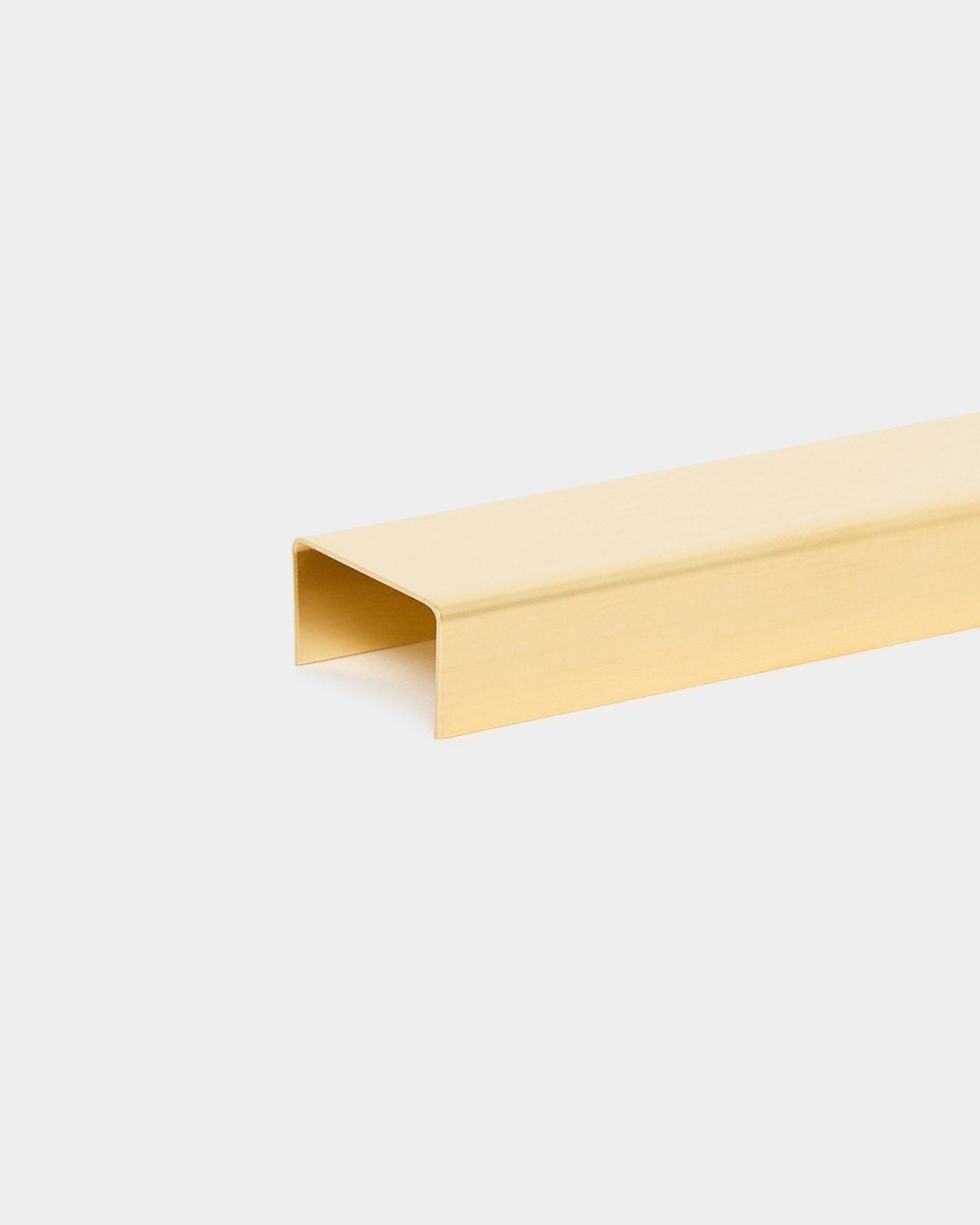 The Liva | Cover in brass, 60 cm by WoodUpp is a U-shaped metal trim accessory for Akupanel acoustic panels, displayed against a plain light gray background.