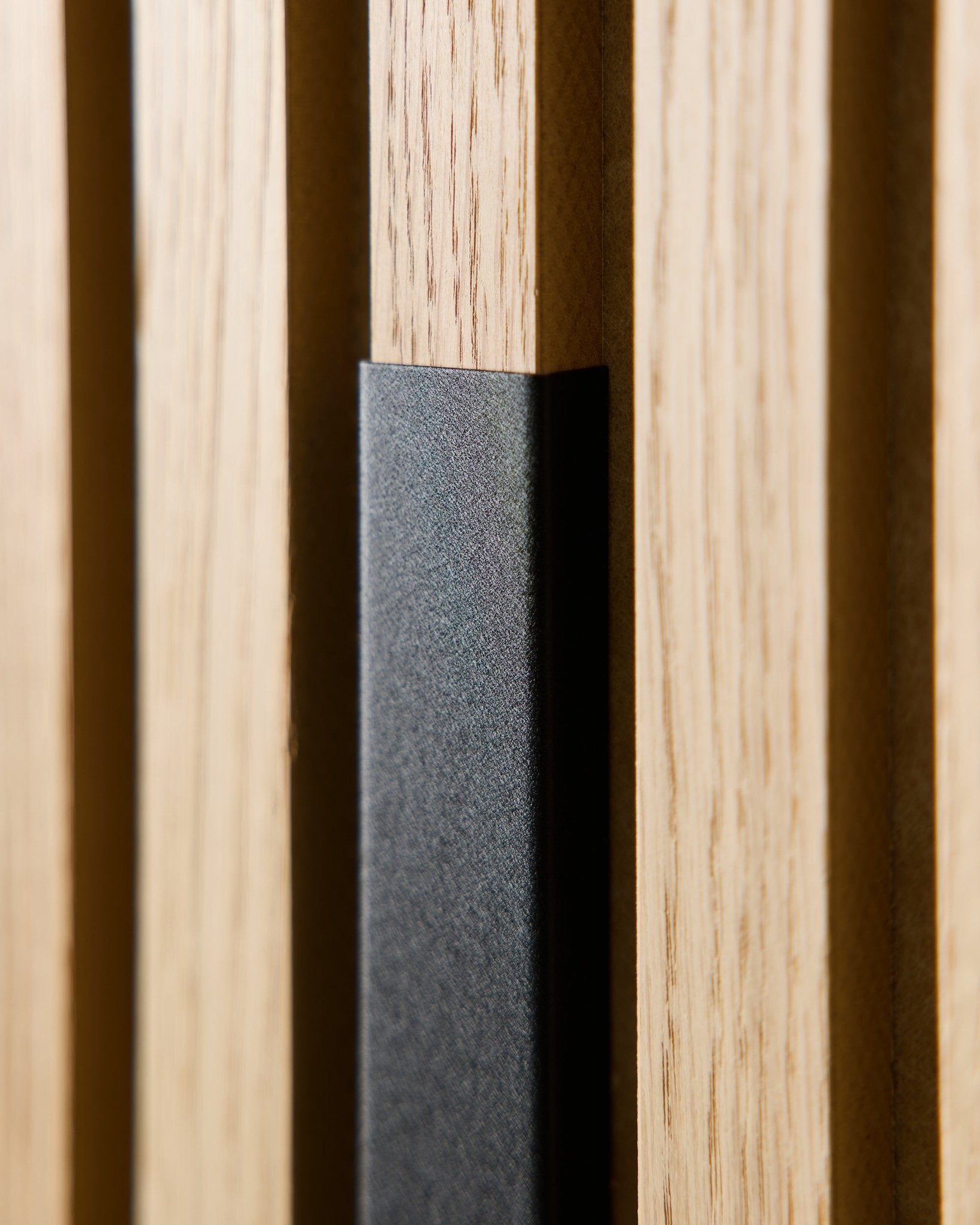 Close-up of WoodUpp Liva acoustic panel with 60 cm black aluminum cover, showing vertical wooden slats and a black accent for modern, Nordic interiors.