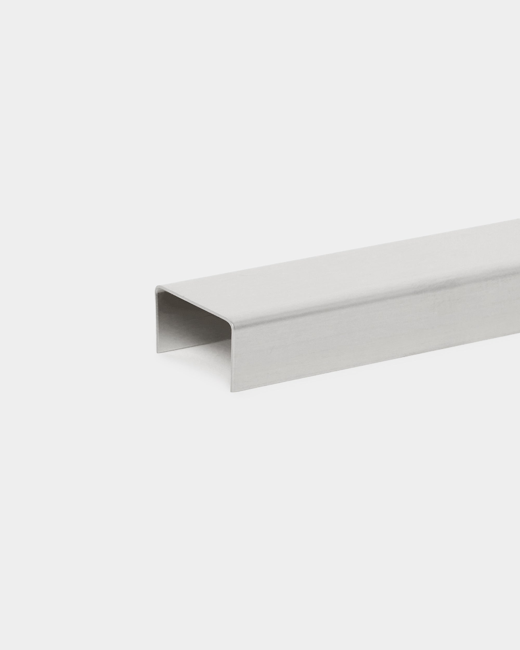 The Liva Cover by WoodUpp, a 20 cm polished steel U-channel accessory, designed as a minimalist wall cover for Akupanel acoustic panels on white backgrounds.