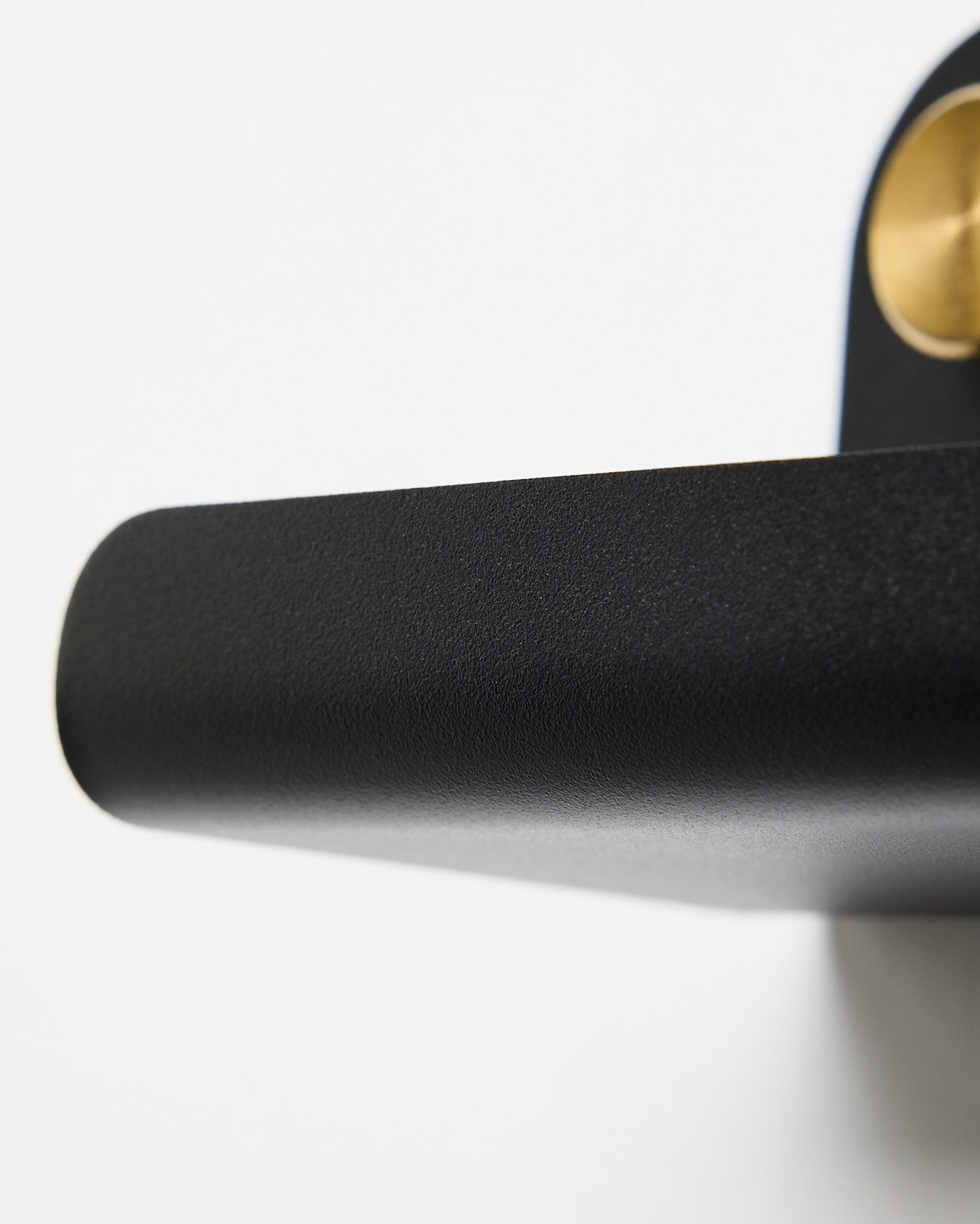 Close-up of a black door handle and the WoodUpp Norr | Narrow Shelf in black, 51.9 cm, positioned against a white background.
