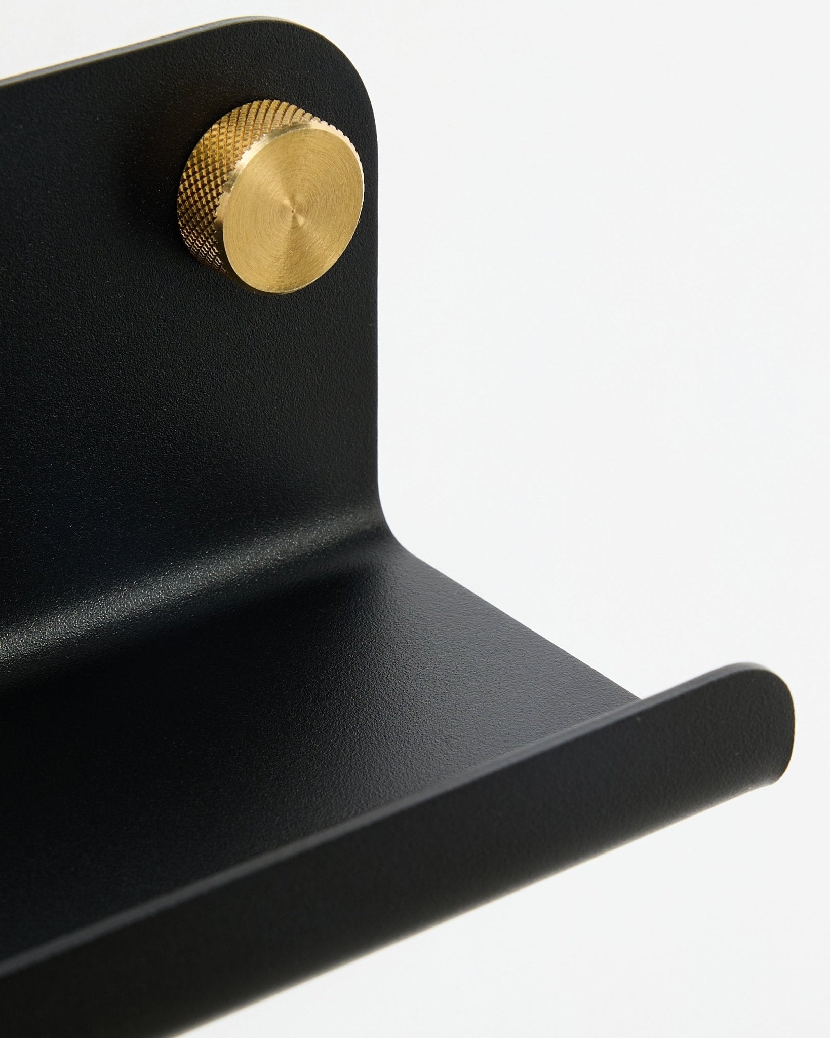 Close-up of WoodUpp Norr Narrow shelf, 35.9 cm, black steel with curved edge and gold knob, shown against a white background.