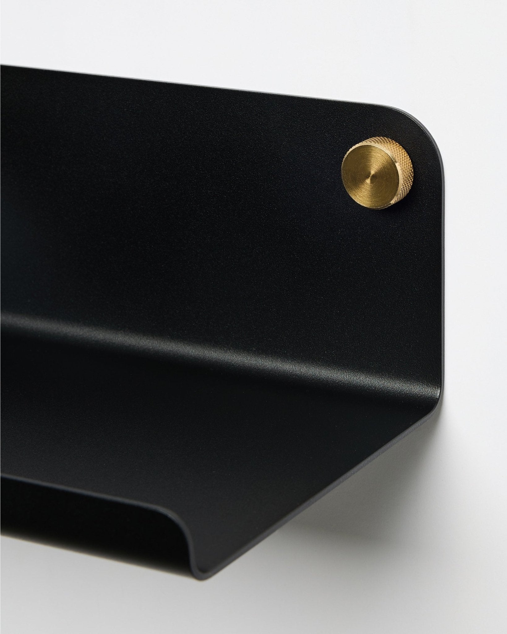Close-up of the WoodUpp Norr Wide Shelf in black, 35.9 cm, with a curved edge, attached to the wall using a round brass screw. Nordic minimalist design.