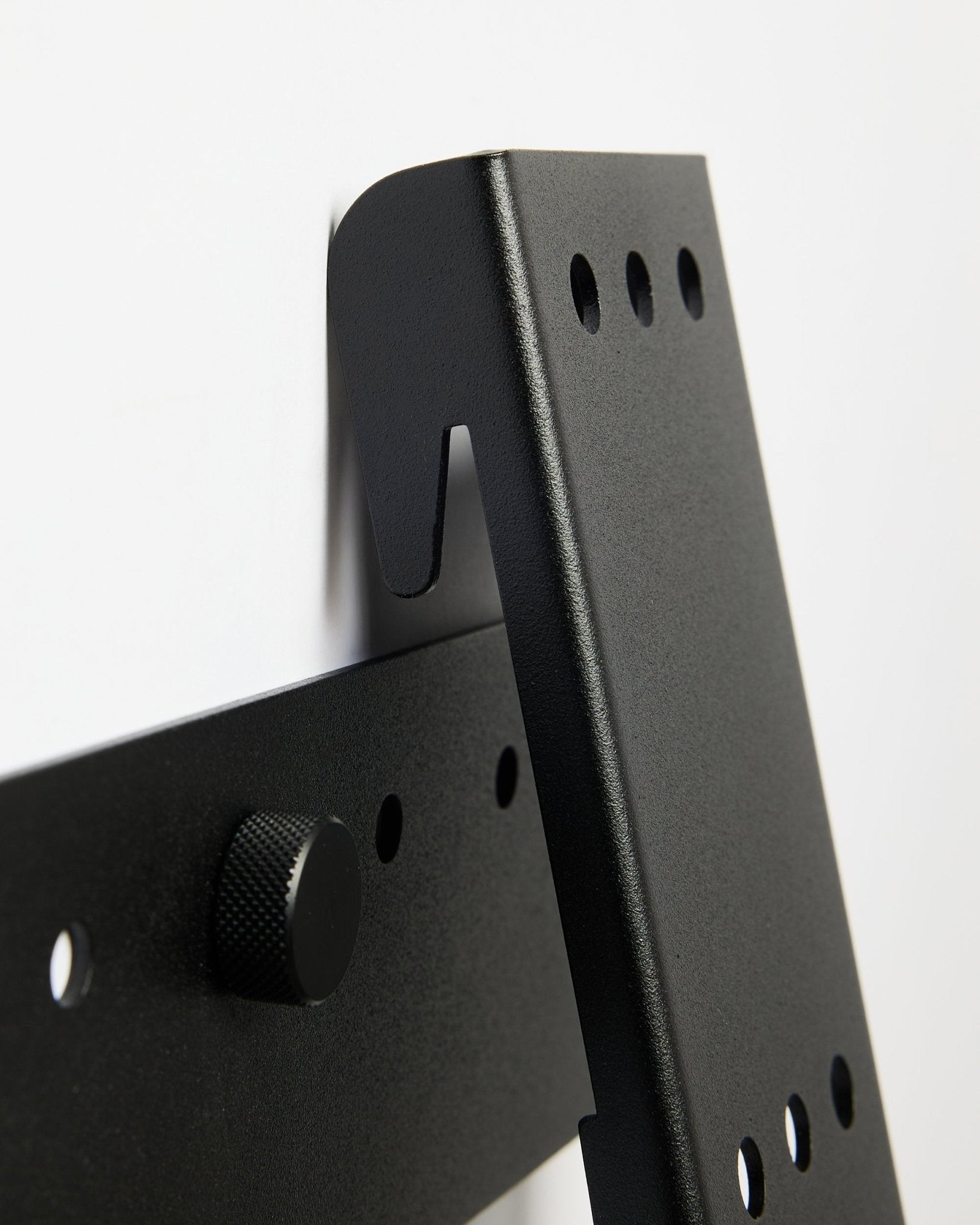 WoodUpp Fjell TV Mount (large), a black metal bracket for 85 TVs with VESA 600x400, mounted on a white wall.