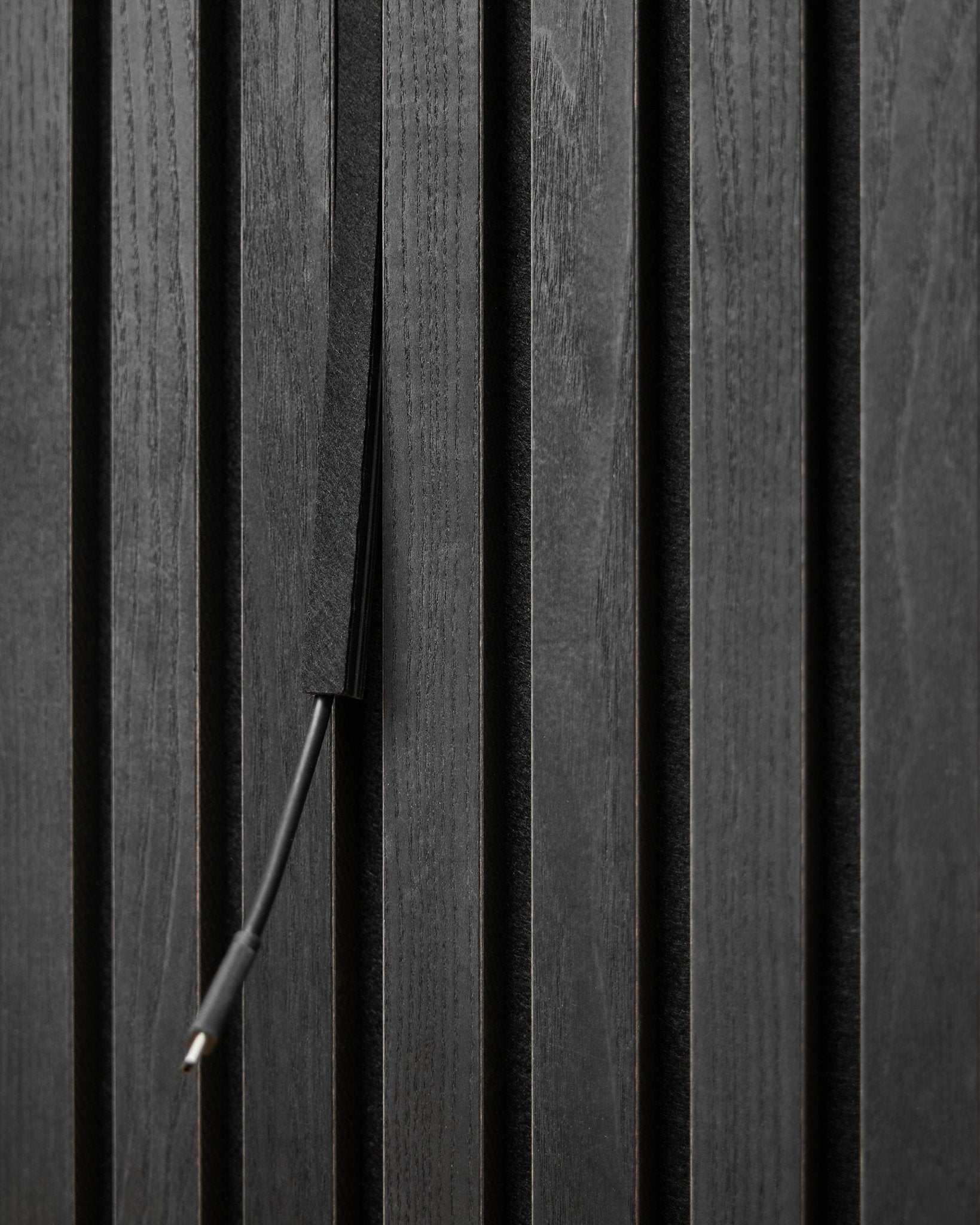 The Dupps Pop-on Cable Cover (Black, 3 pcs) by WoodUpp conceals cables between Akupanel acoustic panel slats for a tidy, integrated appearance.