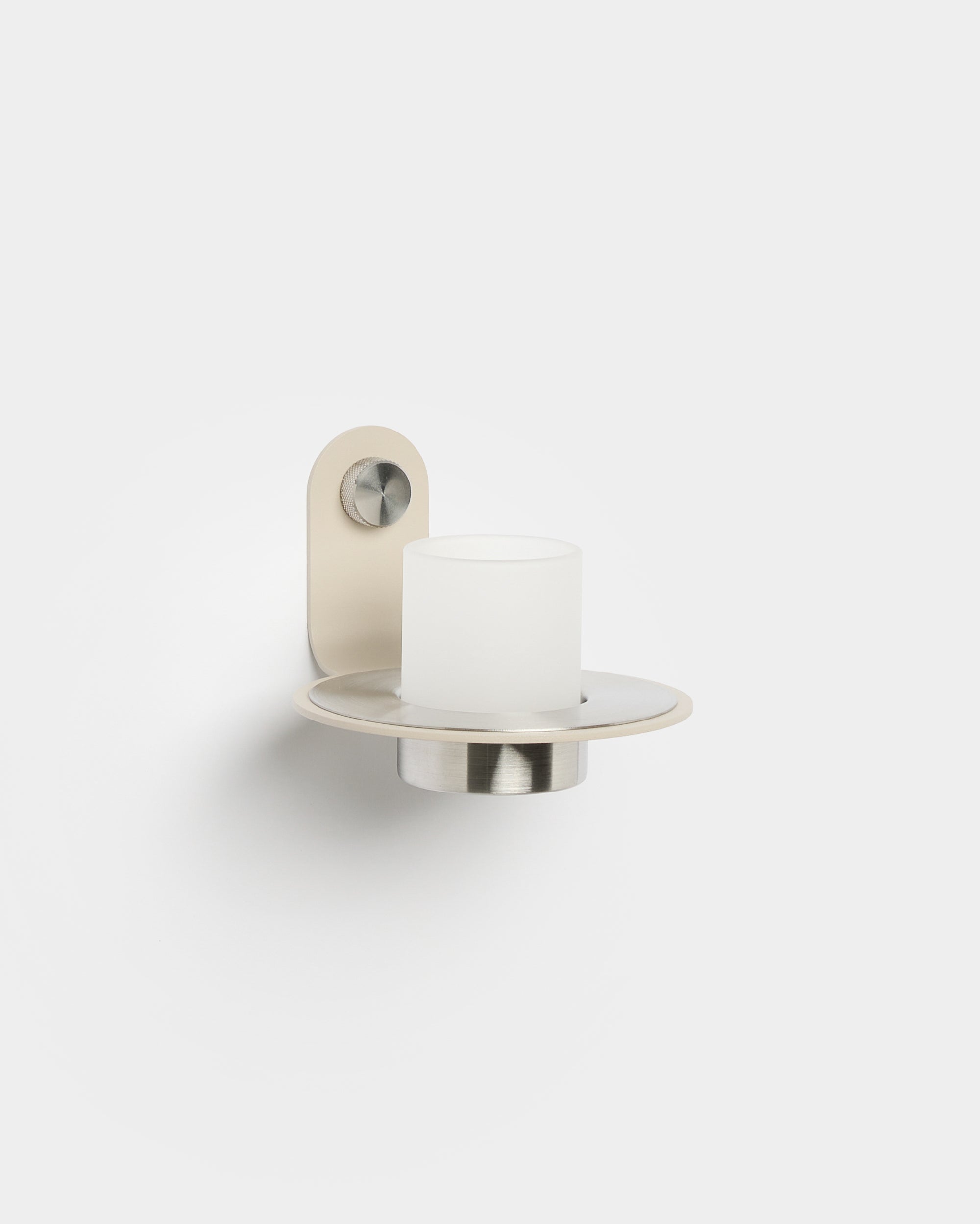 The Norr Candle Holder by WoodUpp, with a beige stainless steel base, placed on an Akupanel acoustic panel for a modern Nordic accent.