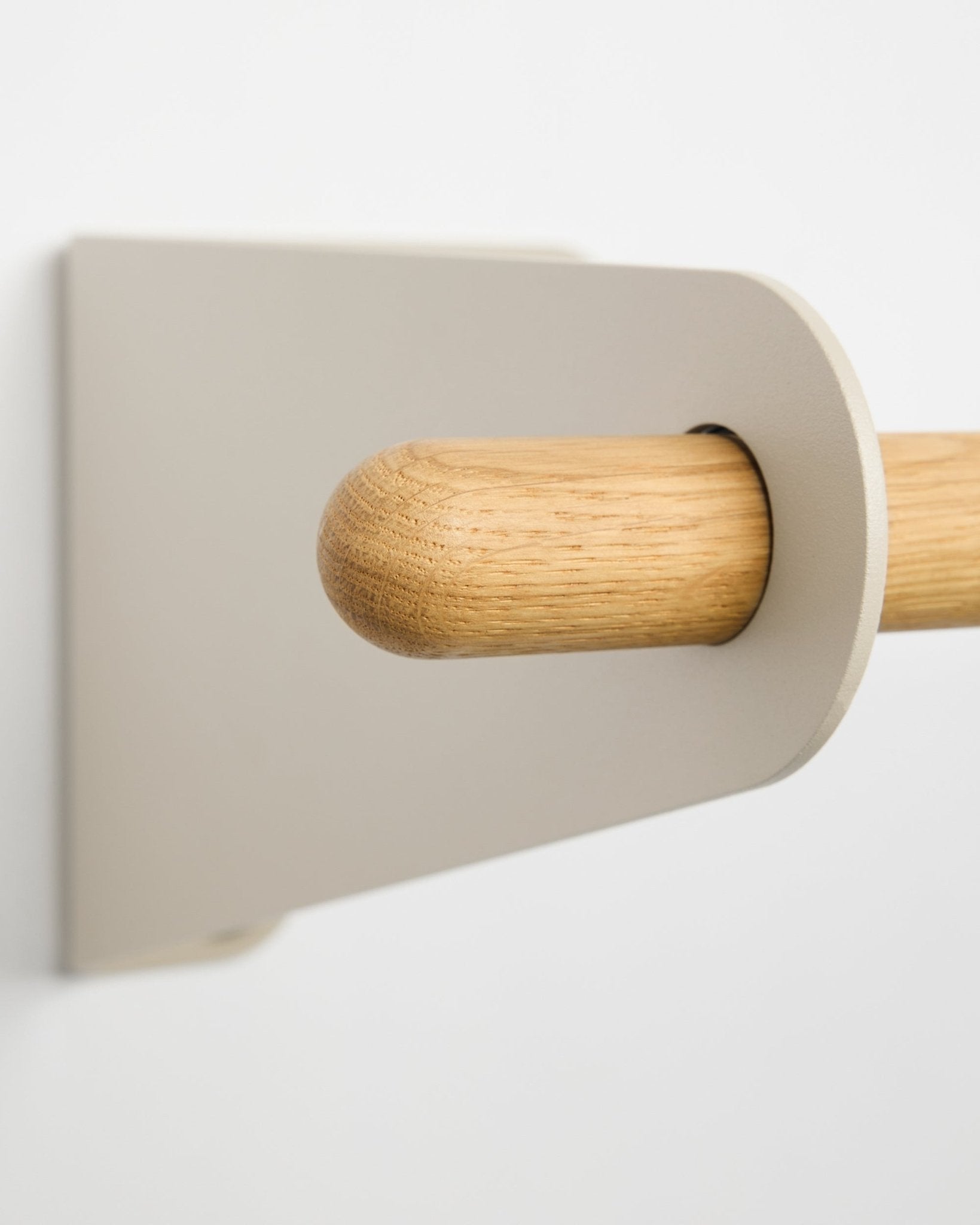 Close-up of the WoodUpp Linn coat rail in beige, 115.9 cm, featuring a light beige metal bracket mounted on a white wall. Nordic minimalist design accessory.