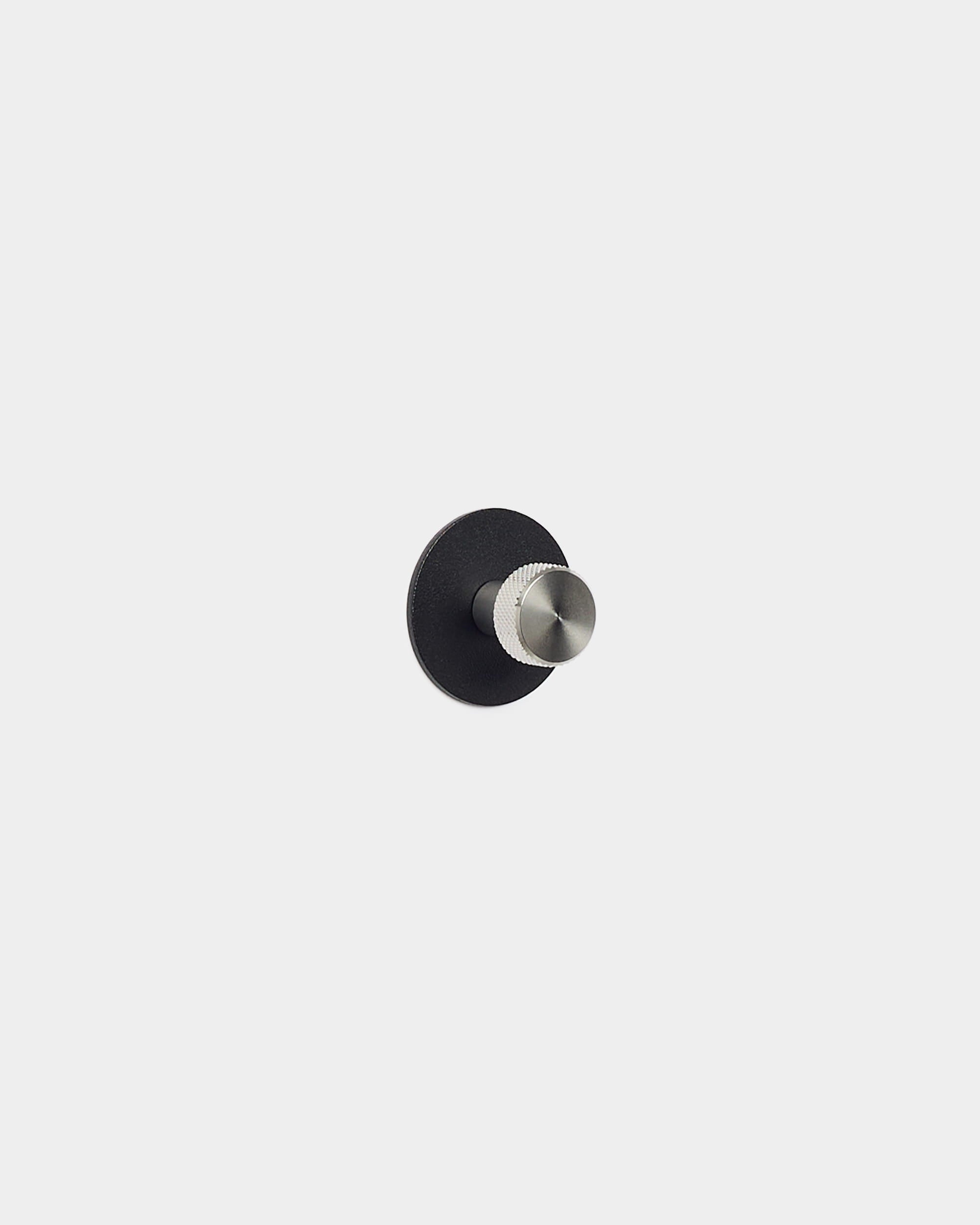 The Norr Coat Hook by WoodUpp has a round black base and silver peg, designed as an accessory for Akupanel acoustic panels—fits minimalist, Nordic spaces.