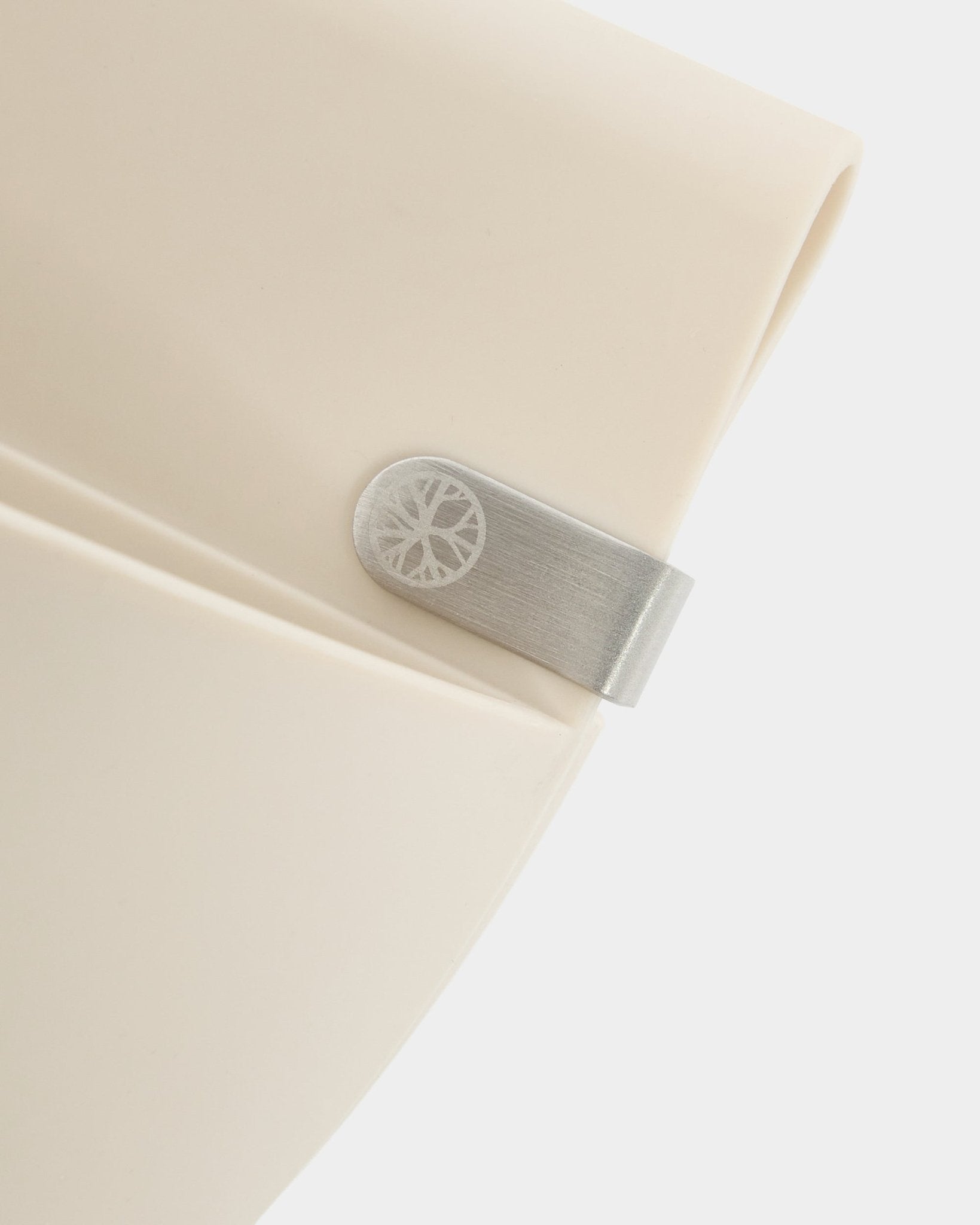 Close-up of a light beige WoodUpp Gro | Soft Pocket / BM2 (4 l) panel with metal clip and engraved circle detail on a plain white background.
