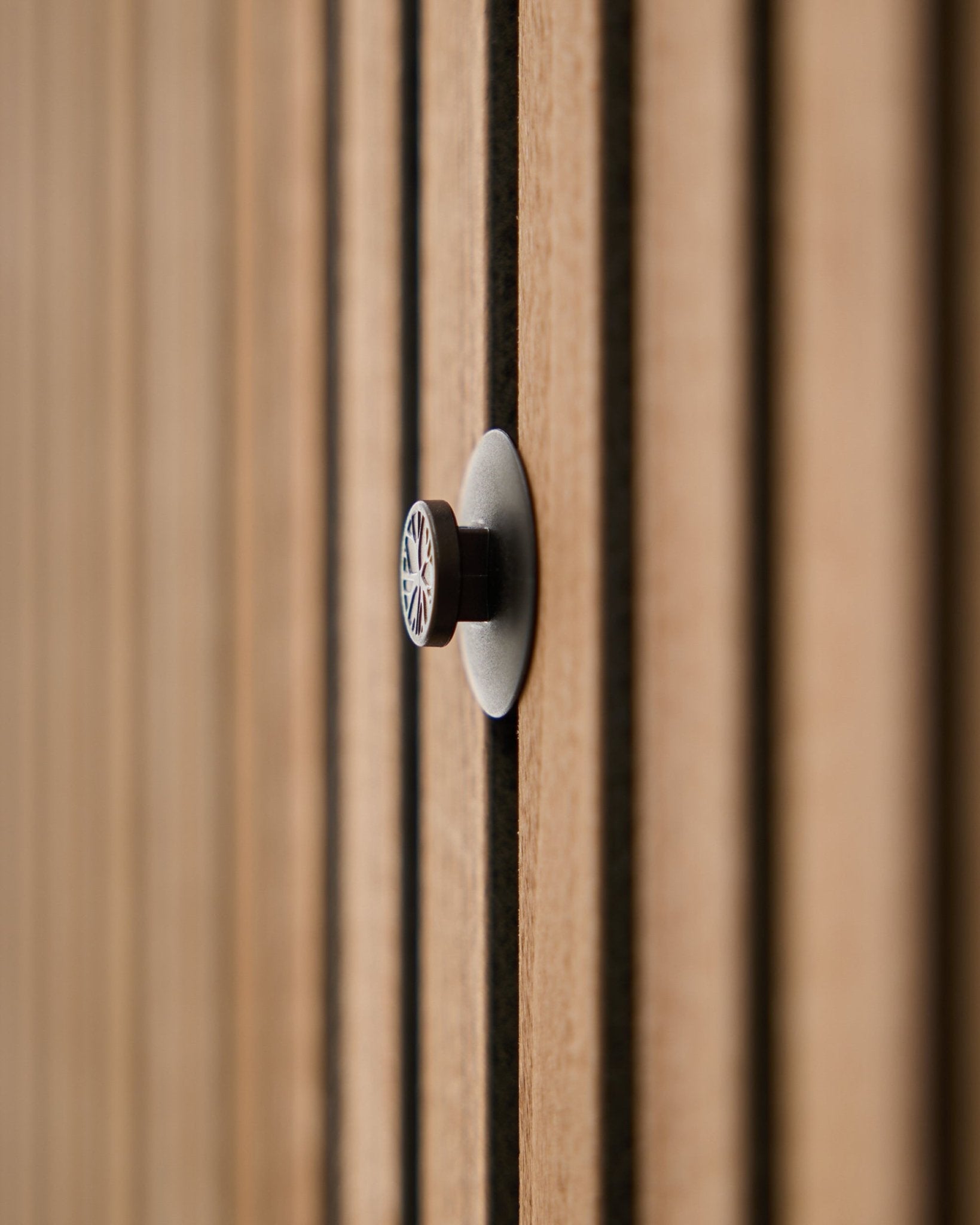Close-up of a Dupps | Light knob set (3 knobs plus tool) by WoodUpp installed on an acoustic slatwall panel, with wooden slats softly blurred in the background.