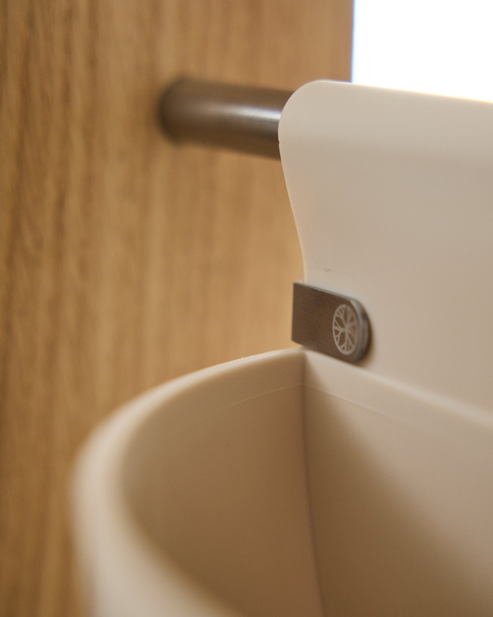 Close-up of Gro | Soft Pocket / BM2 (4 l) in light beige by WoodUpp, hanging on a metal rod mounted to wood; blurred background. Nordic acoustic accessory.